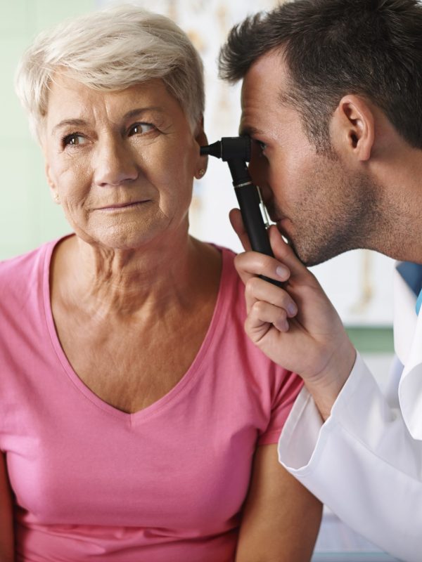 Doctor examining ear of senior woman
