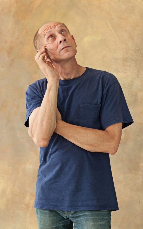 Worried mature man touching his head and thinking on studio background.